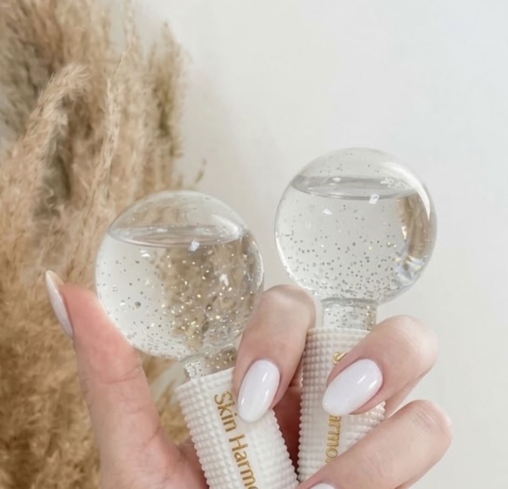 Dos ice globes con el nombre Skin Harmony en el mango, sostenidos junto a plumas de pampa.